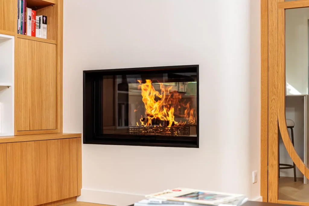 Cheminée sur mesure encastrée dans un mur avec habillage bois et flamme en fonctionnement – Cheminées Nicolas