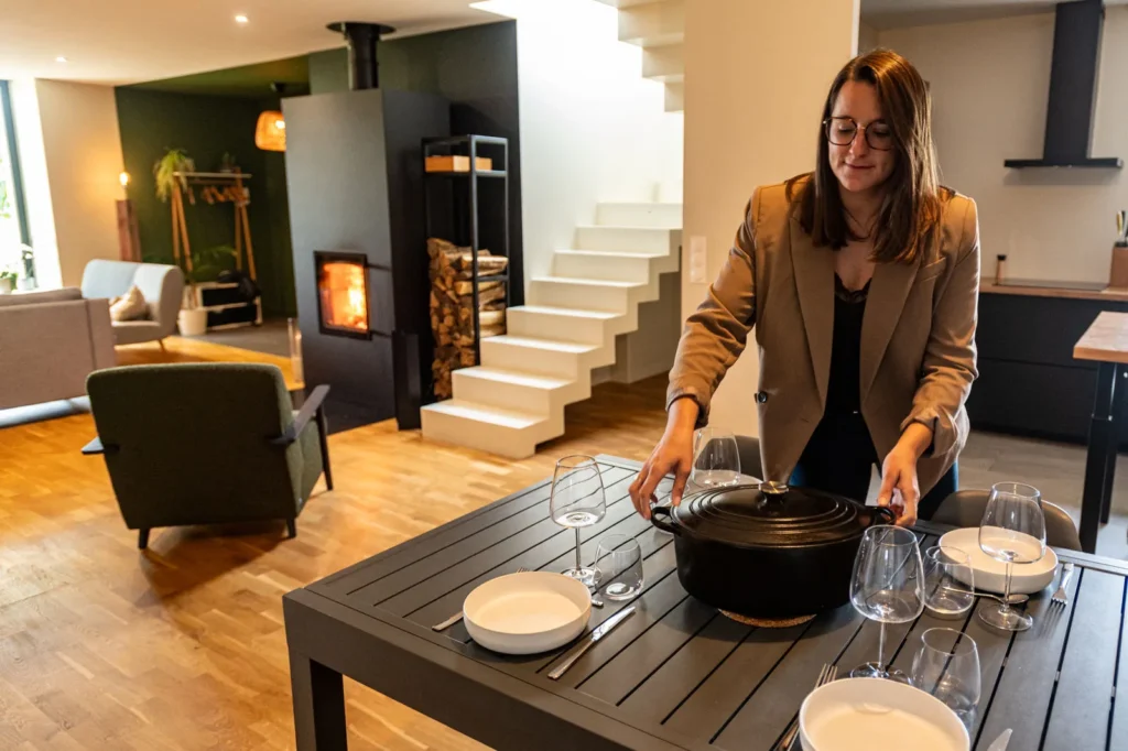 Poêle de masse Tulikivi Raita 21 Color rayonnant dans une cuisine ouverte et salle à manger lors d'un repas de famille.